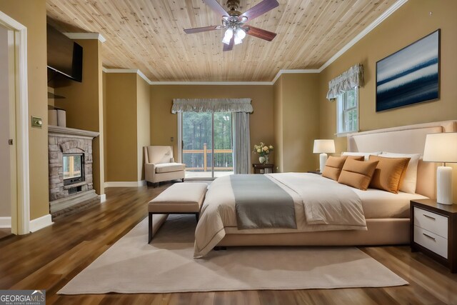 bedroom with ceiling fan, crown molding, light hardwood / wood-style flooring, a stone fireplace, and wood ceiling