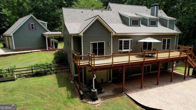 rear view of house featuring a deck, a carport, and a lawn