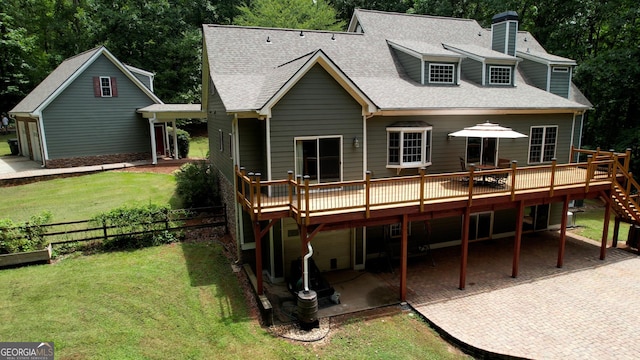 back of property featuring a lawn, a patio, roof with shingles, fence, and a deck