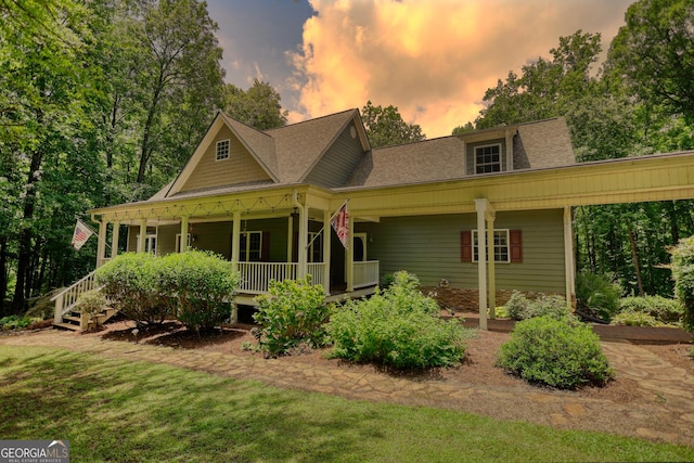 view of front of property with a yard, a porch, and a shingled roof