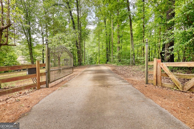 view of street with aphalt driveway, a gate, and a gated entry