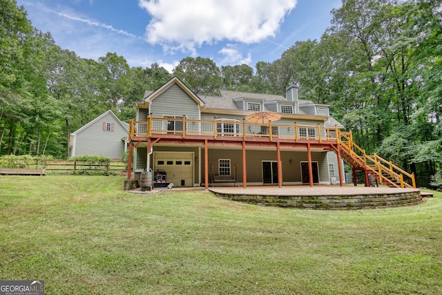 rear view of house with a garage, a wooden deck, a lawn, and a patio area