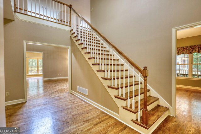 stairs with wood-type flooring and a high ceiling