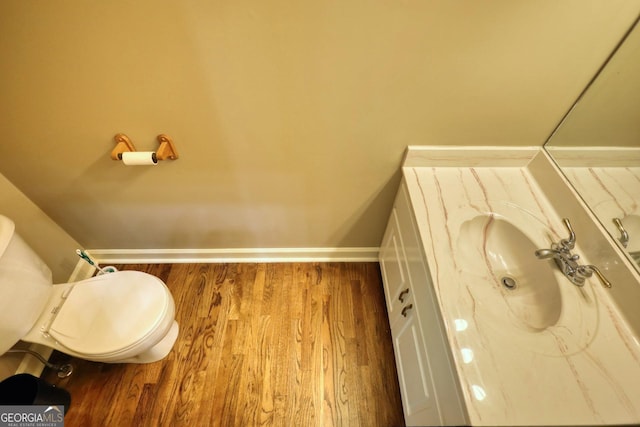 half bath featuring vanity, wood finished floors, toilet, and baseboards