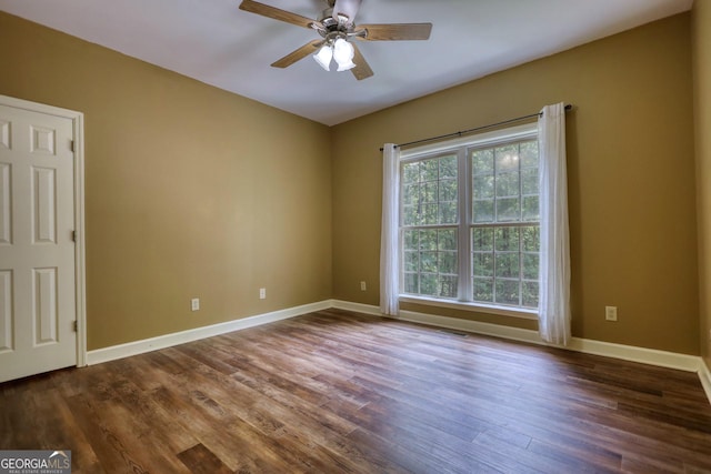 unfurnished room with dark wood-style floors, visible vents, baseboards, and a ceiling fan