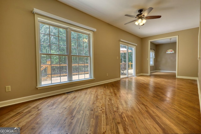 unfurnished room with ceiling fan, wood finished floors, and baseboards