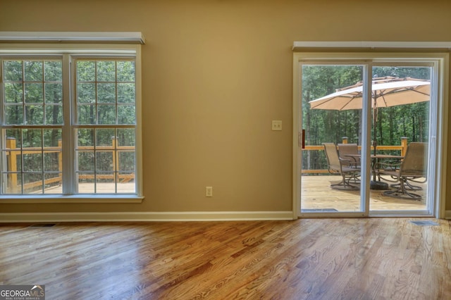 interior space featuring a healthy amount of sunlight, baseboards, visible vents, and wood finished floors