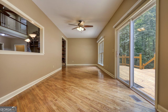 spare room with a ceiling fan, visible vents, light wood-style flooring, and baseboards