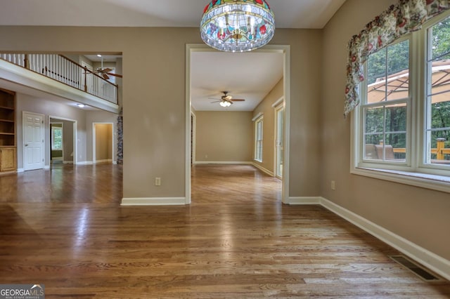 unfurnished room with hardwood / wood-style flooring and ceiling fan with notable chandelier