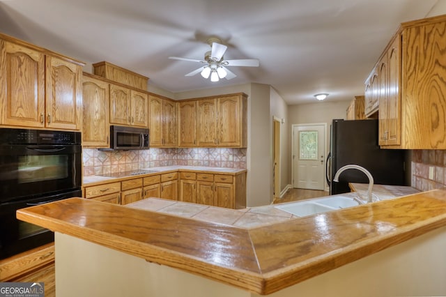 kitchen featuring black appliances, kitchen peninsula, and backsplash