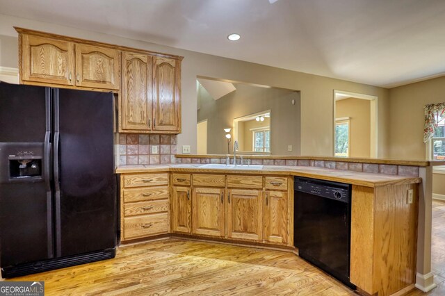 kitchen featuring sink, kitchen peninsula, black appliances, and light hardwood / wood-style floors