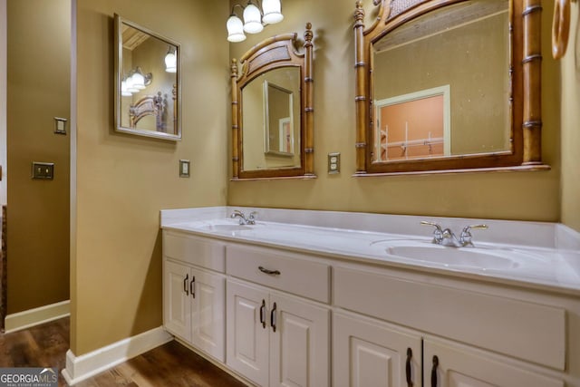 full bathroom featuring wood finished floors, a sink, baseboards, and double vanity