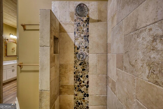 details featuring vanity, a tile shower, and hardwood / wood-style floors