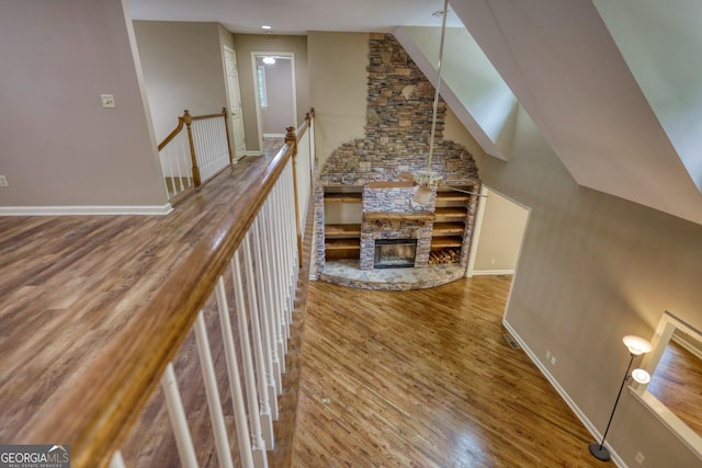 unfurnished living room with baseboards, a fireplace, high vaulted ceiling, and wood finished floors