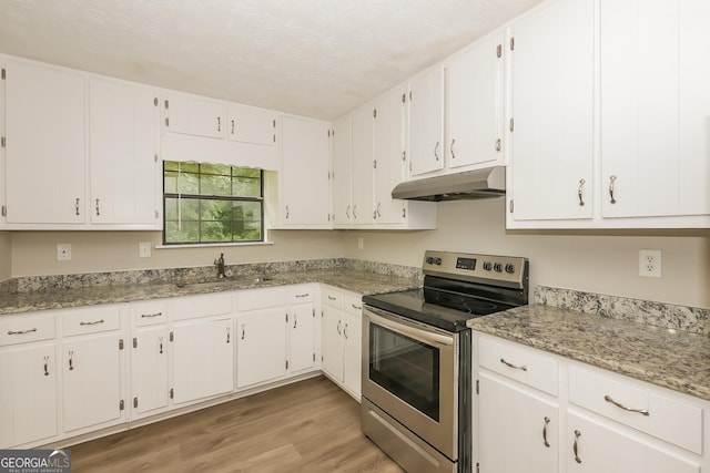 kitchen featuring sink, stainless steel range with electric stovetop, light stone counters, white cabinets, and light wood-type flooring