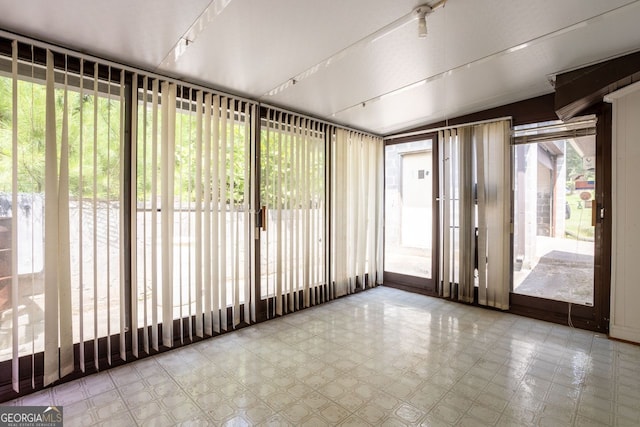 unfurnished sunroom with a healthy amount of sunlight and rail lighting