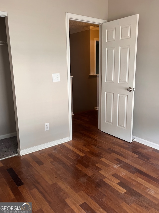 unfurnished bedroom with a closet and dark wood-type flooring