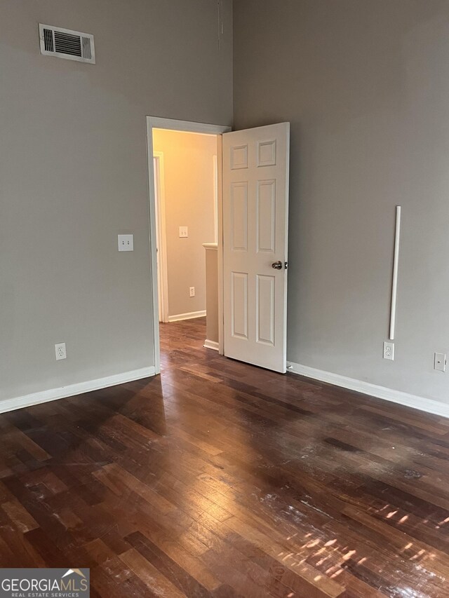 unfurnished room featuring dark hardwood / wood-style floors and a high ceiling