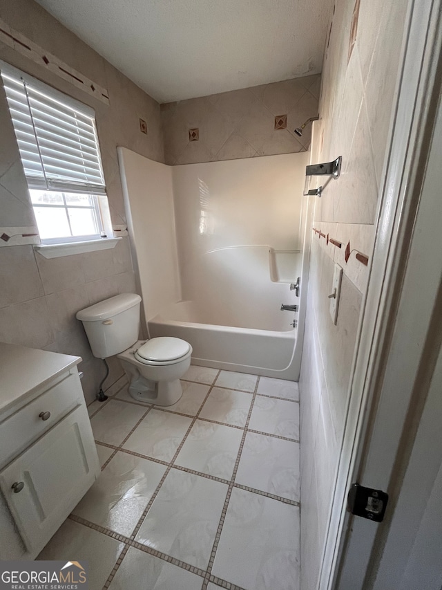 full bathroom featuring shower / bath combination, toilet, vanity, tile walls, and tile patterned floors