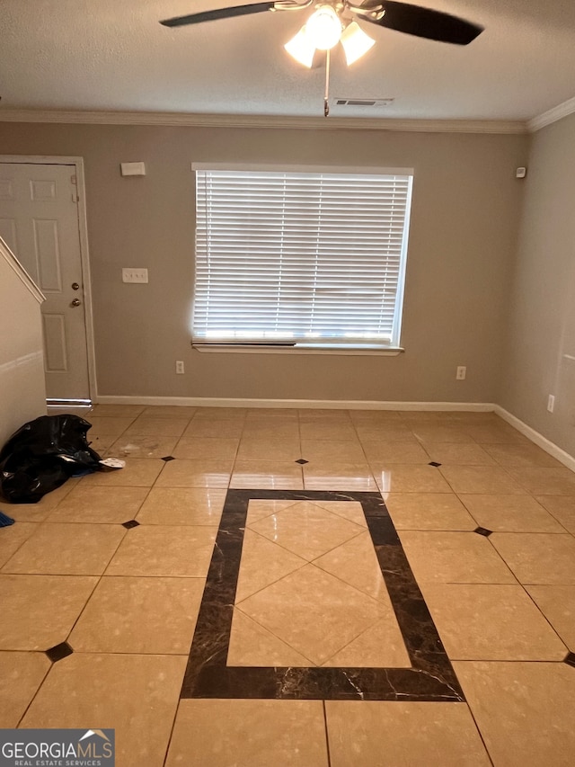 tiled empty room with ceiling fan, a textured ceiling, and ornamental molding