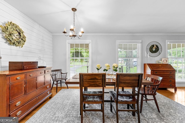 dining space with a notable chandelier, crown molding, wood-type flooring, and wood walls