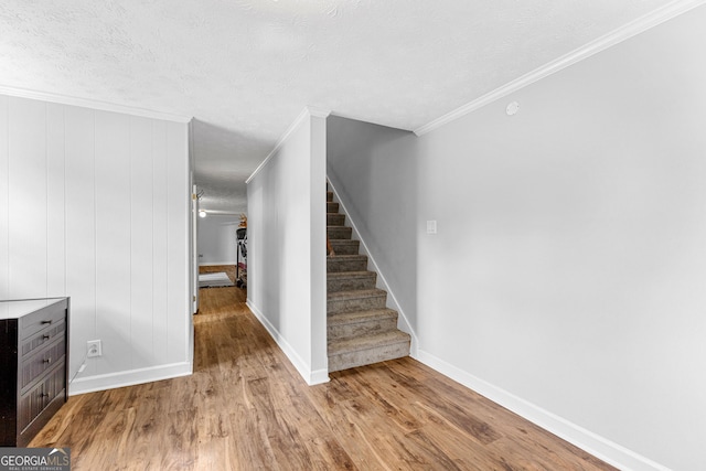 interior space featuring crown molding, wood-type flooring, and a textured ceiling