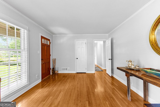 foyer entrance with ornamental molding, a healthy amount of sunlight, and light wood-type flooring