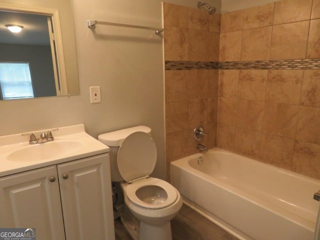 full bathroom featuring tiled shower / bath, vanity, and toilet