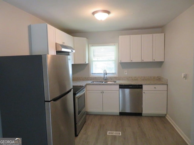 kitchen featuring white cabinetry, sink, light stone countertops, and appliances with stainless steel finishes