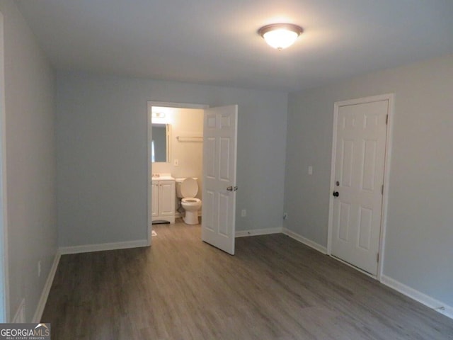 unfurnished bedroom featuring hardwood / wood-style floors, a closet, and ensuite bathroom