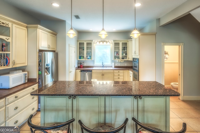 kitchen featuring sink, a kitchen island, appliances with stainless steel finishes, and light tile patterned floors