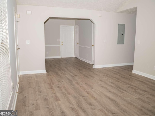 unfurnished room with a textured ceiling, hardwood / wood-style flooring, and electric panel