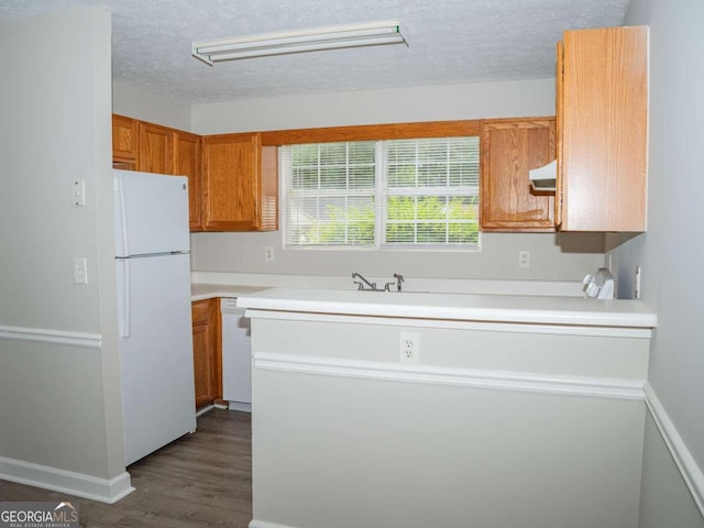 kitchen featuring kitchen peninsula, dark hardwood / wood-style flooring, white appliances, and a textured ceiling