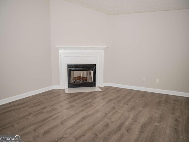 unfurnished living room with hardwood / wood-style flooring, a multi sided fireplace, and a textured ceiling