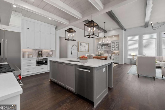 kitchen featuring sink, appliances with stainless steel finishes, an island with sink, pendant lighting, and white cabinets