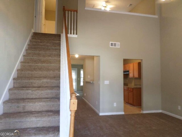 stairway with carpet floors and high vaulted ceiling