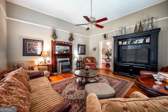 living room with ornamental molding, wood-type flooring, and ceiling fan