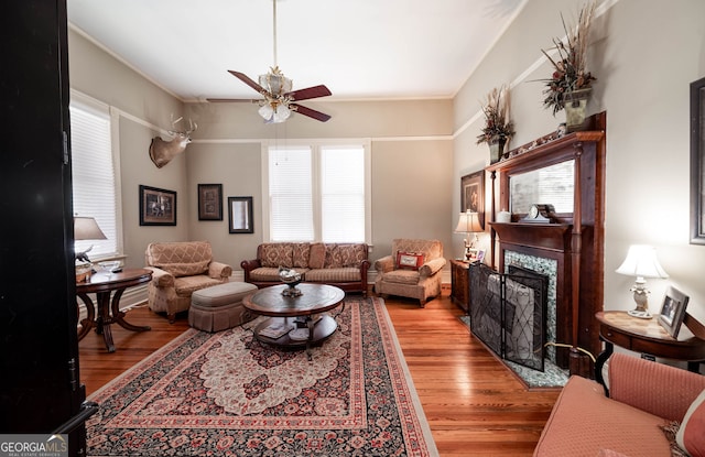 living room featuring ornamental molding, a premium fireplace, ceiling fan, and hardwood / wood-style floors