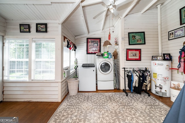 clothes washing area featuring wood-type flooring, ceiling fan, gas water heater, wooden walls, and washer and dryer