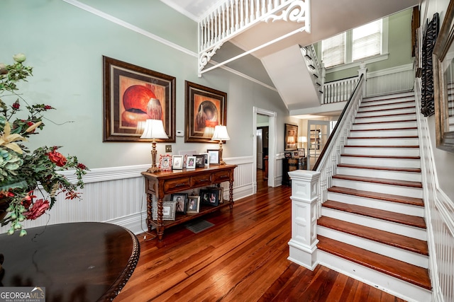 entryway with crown molding, hardwood / wood-style floors, and high vaulted ceiling