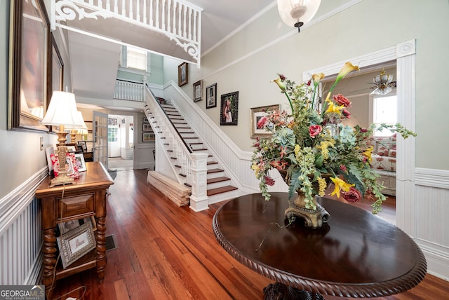 foyer entrance with ornamental molding, hardwood / wood-style flooring, a towering ceiling, and ceiling fan