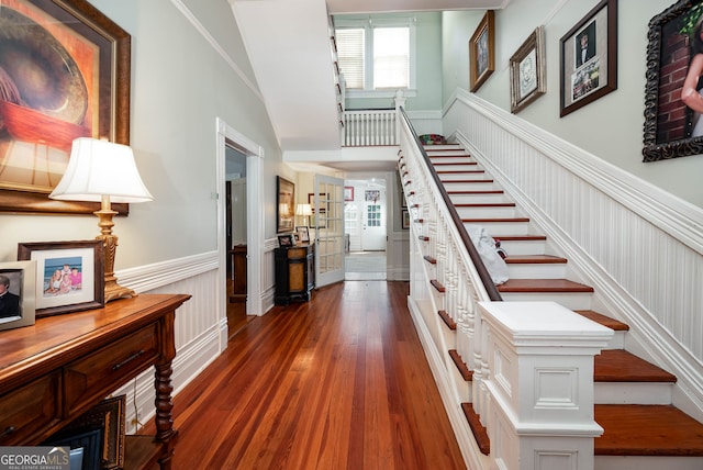 stairs featuring crown molding, a towering ceiling, and dark hardwood / wood-style flooring