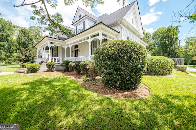 view of side of property featuring covered porch and a yard