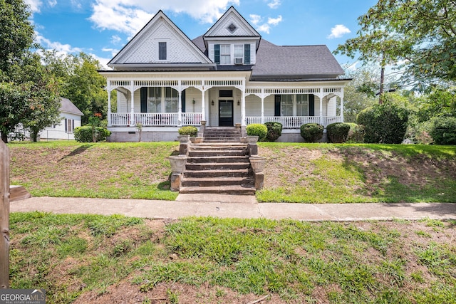 victorian home with a porch, a garage, and an outbuilding