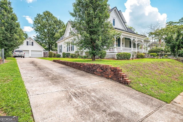 view of front facade with a garage, covered porch, an outbuilding, and a front yard