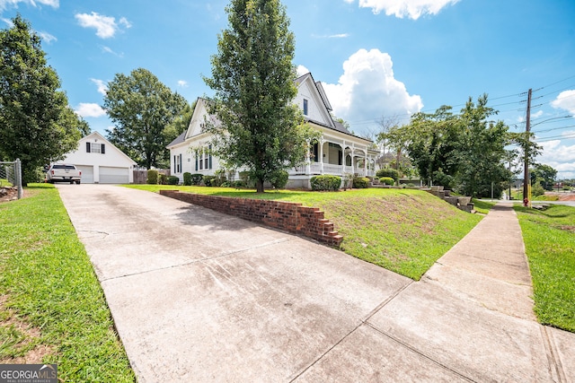 view of front of home featuring covered porch, an outbuilding, a garage, and a front yard