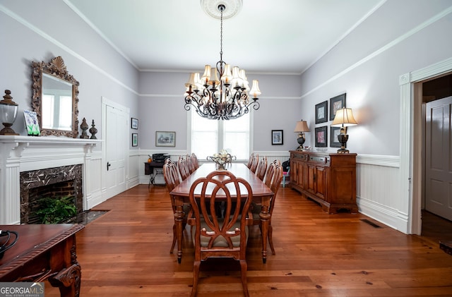 dining area featuring ornamental molding, a fireplace, hardwood / wood-style flooring, and a chandelier