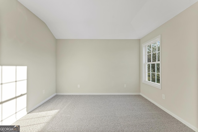 carpeted empty room featuring vaulted ceiling