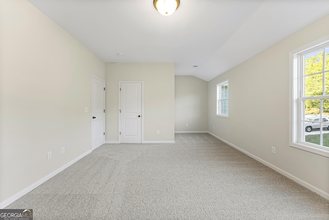 carpeted empty room featuring lofted ceiling