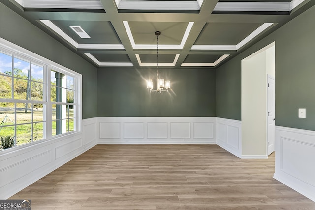 spare room with plenty of natural light, an inviting chandelier, beam ceiling, and coffered ceiling